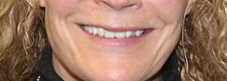 The image is a close-up of a person smiling and looking directly at the camera.