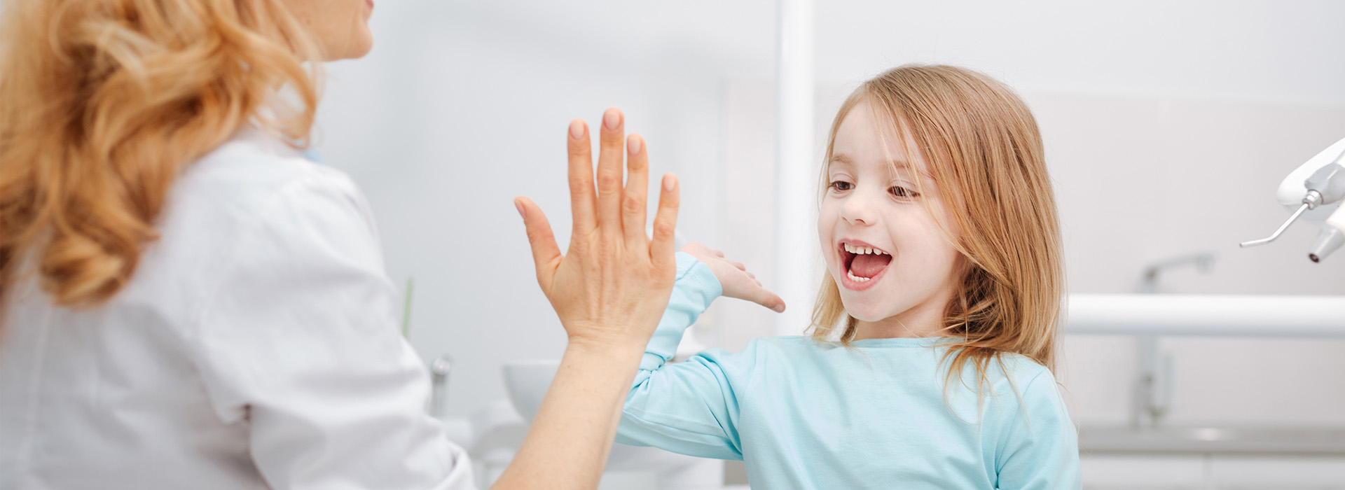 A woman and a young girl in a bathroom, with the woman gesturing towards the child.